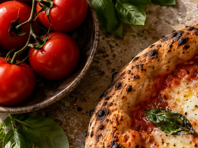 Fresh tomatoes and basil beside a pizza